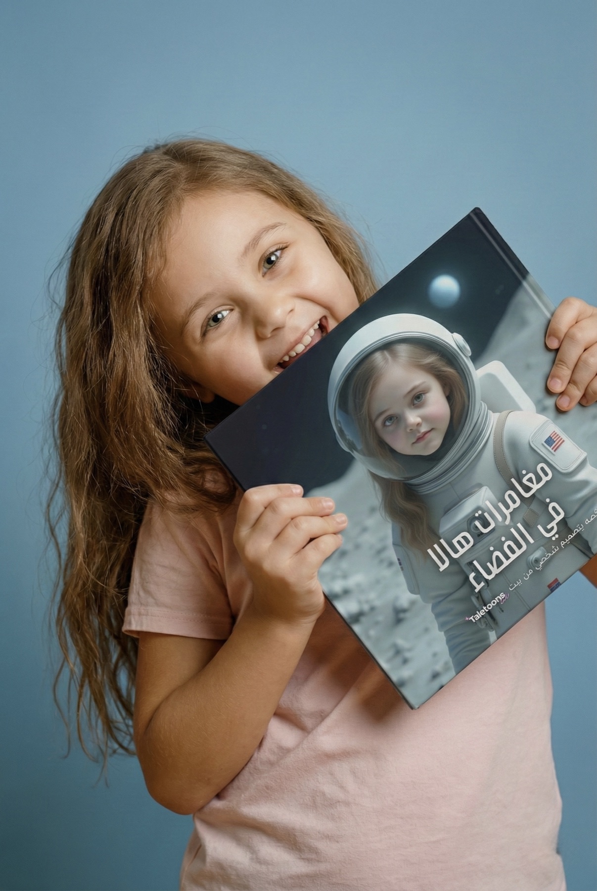 A girl holding her personalized Taletoons space adventure book in a blue studio